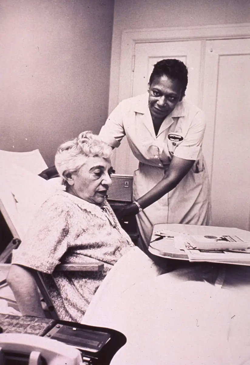A nurse caring for a woman resting in bed