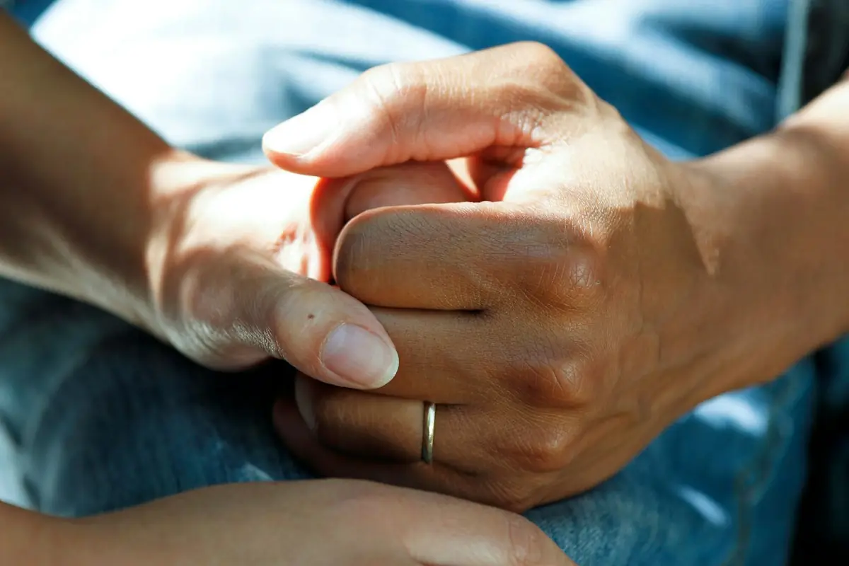 Close-up of a caregiver's hands holding a client's hand